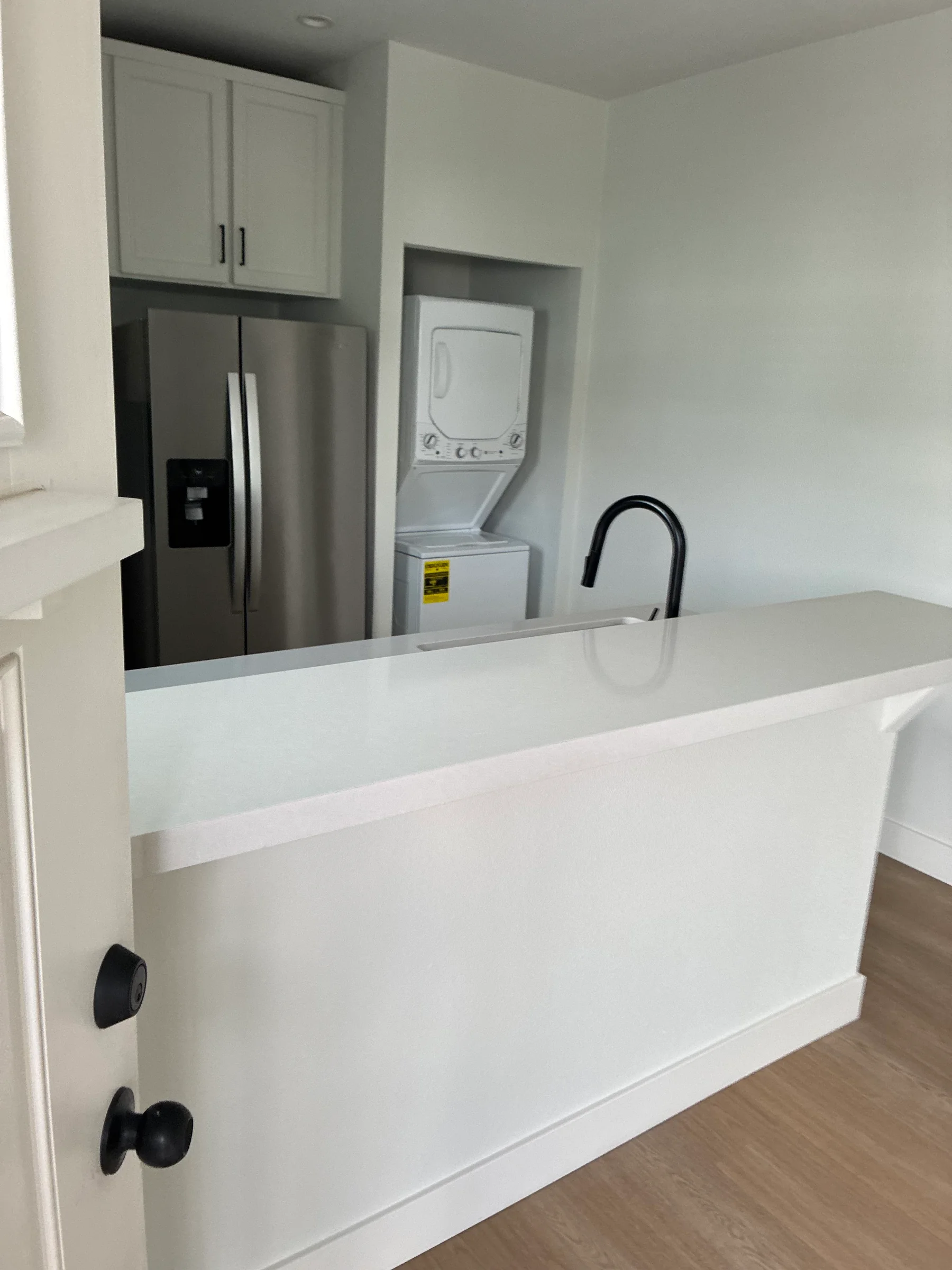 Clean kitchen counter with sink, faucet and fridge