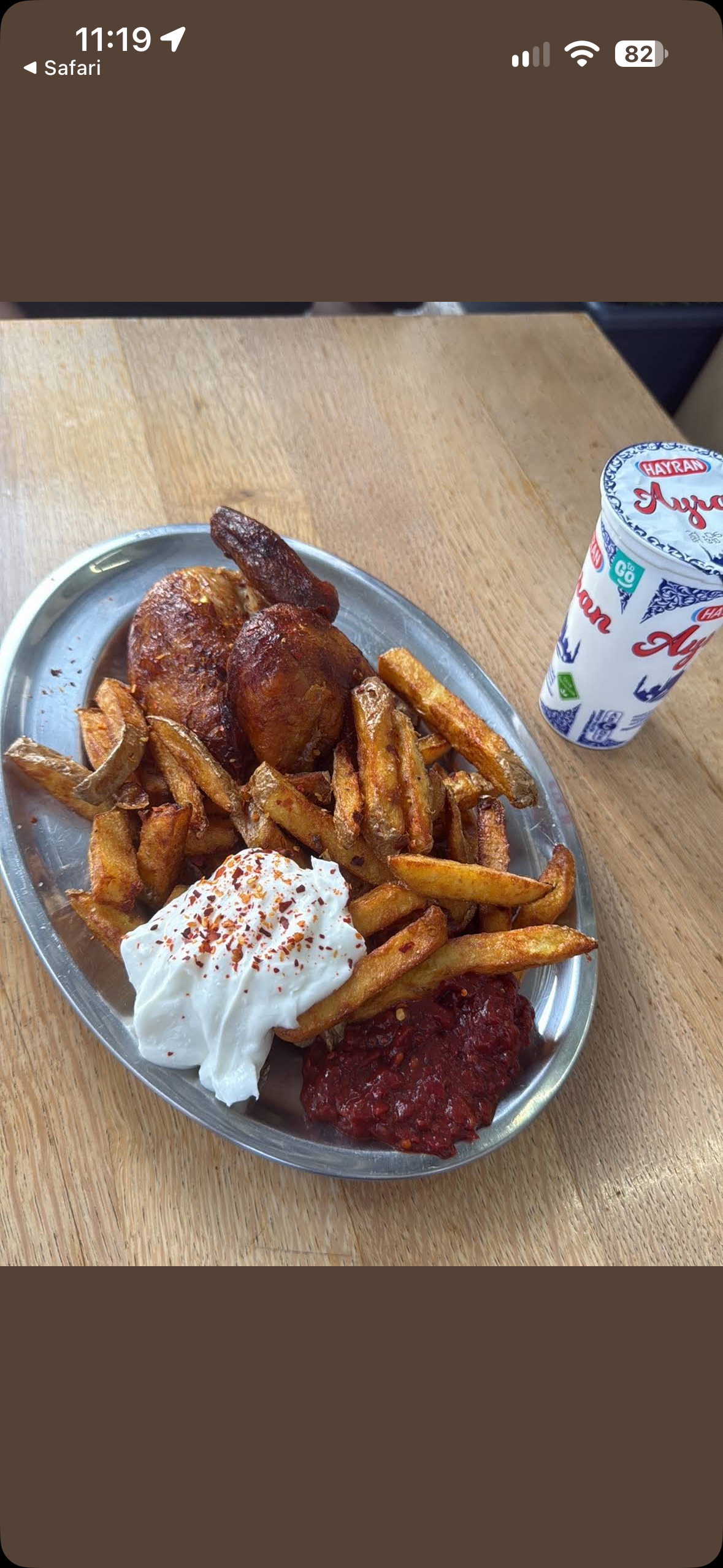 Grillhähnchen mit Holland Pommes, Joghurt mit Chiliflocken und scharfer Soße auf einer Metallplatte, daneben ein Ayran