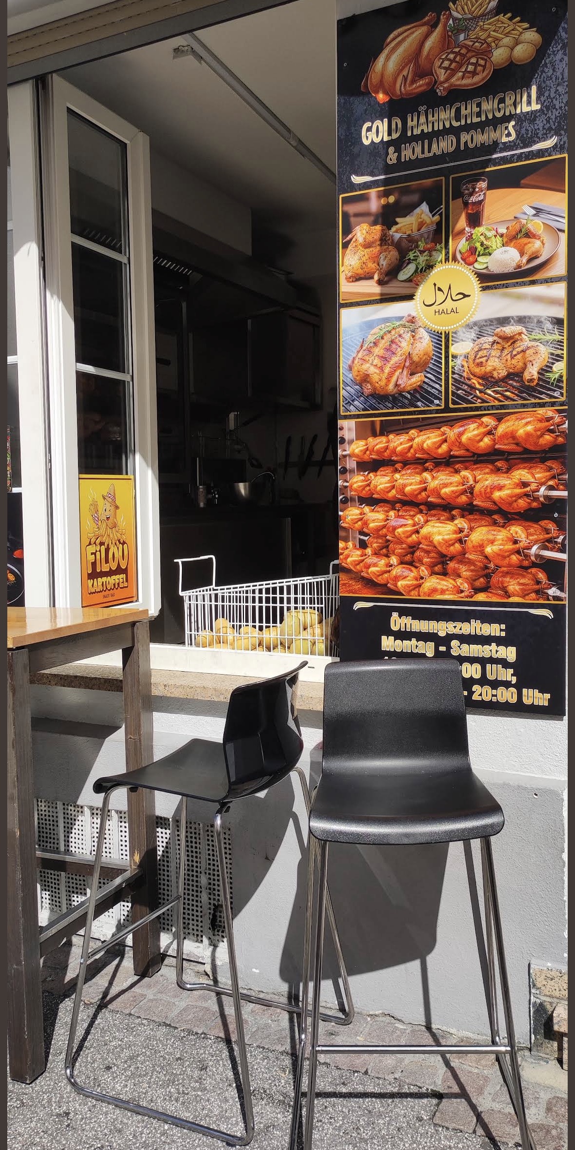 Offenes Fenster des Ladens mit einem Korb frischer Kartoffeln, zwei Barhockern und dem Schild mit Öffnungszeiten