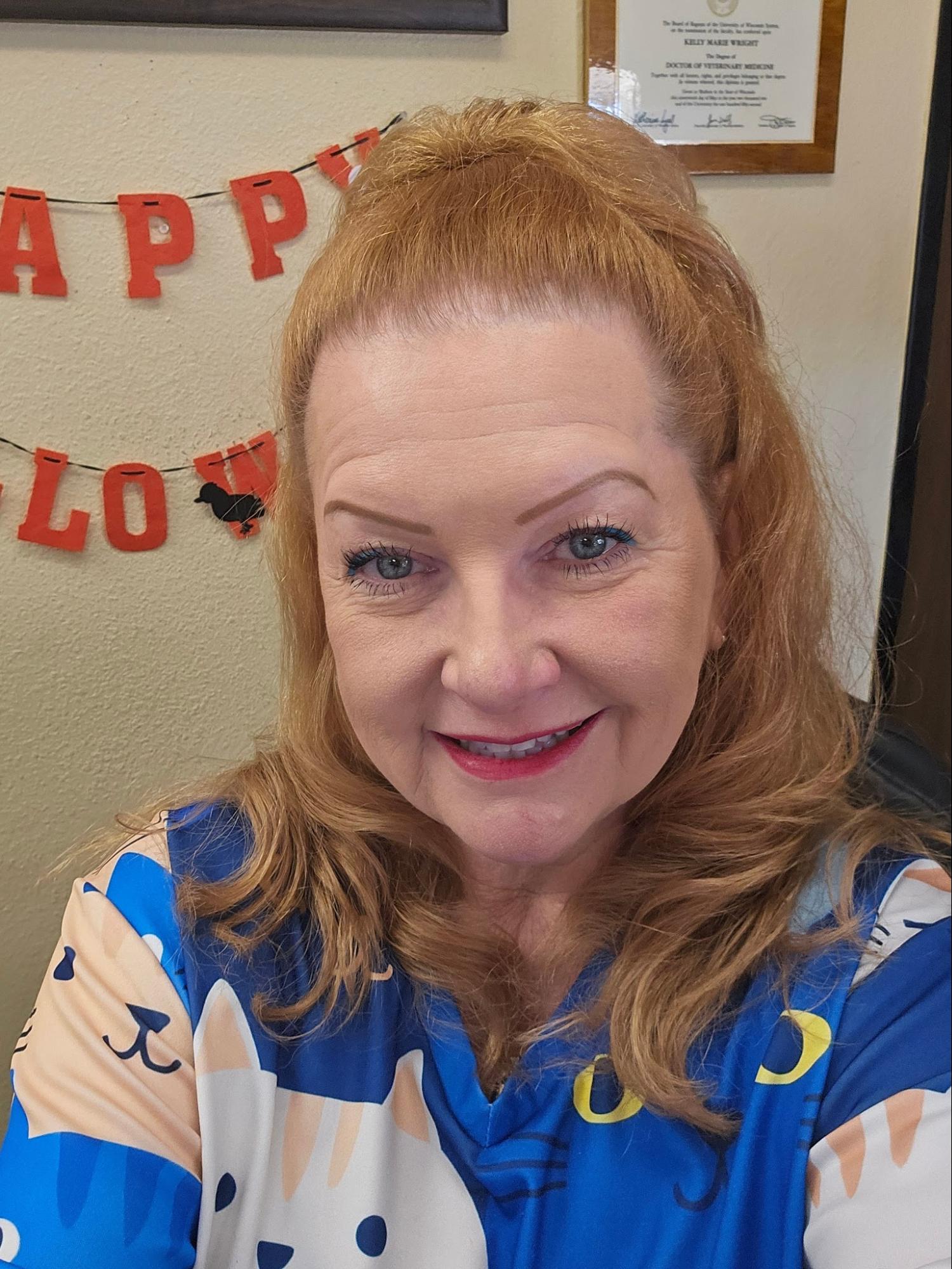 Toni Powell smiling, wearing a blue top with cat faces
