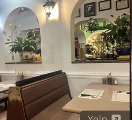 A booth and set tables in the Mi Tierrita dining room, with arched openings and plants