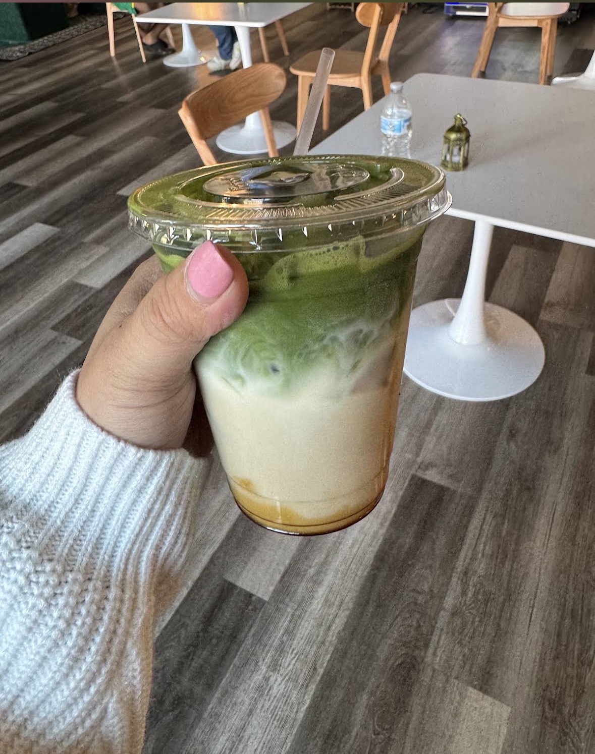An iced matcha latte held up in the café dining room