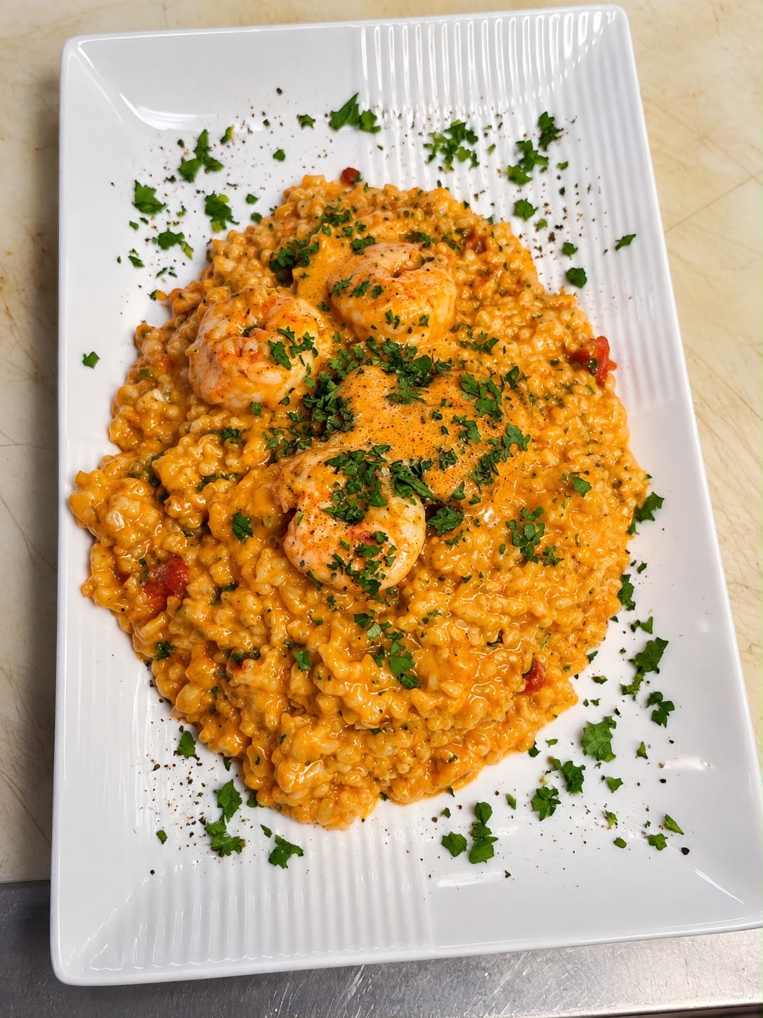 Risotto mit Garnelen und Petersilie auf einem weißen Teller