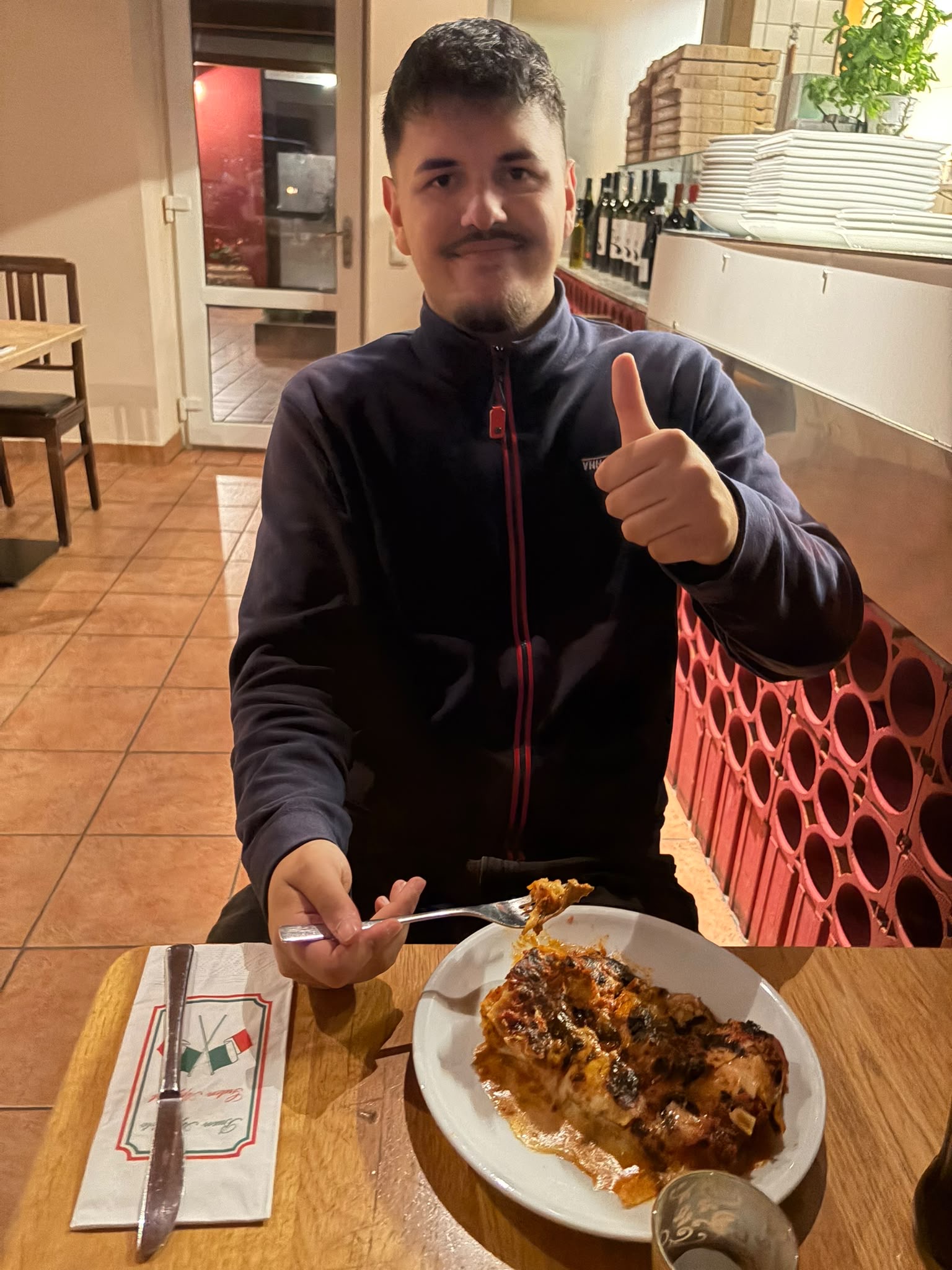 Gast im Restaurant mit Lasagne und erhobenem Daumen