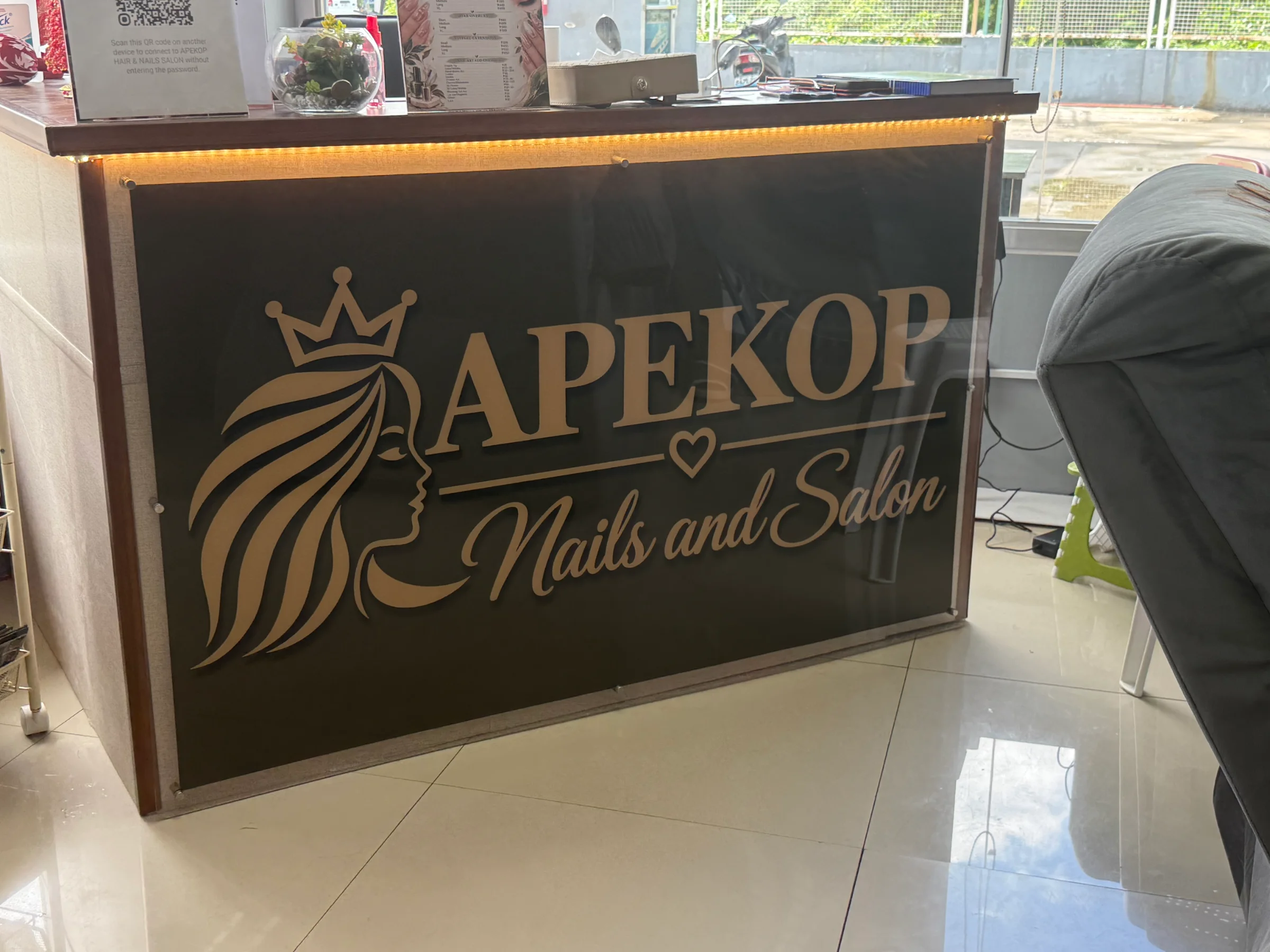 The reception desk at Apekop with the gold crown and Nails and Salon sign
